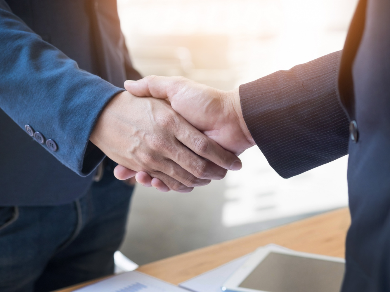 Close-up of two business professionals shaking hands, symbolizing trust, agreements, and the idea that people buy promises, not just products.