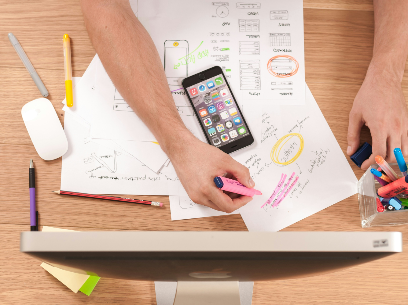 Person planning a Giving Tuesday marketing campaign at a desk with notes, sketches, and a smartphone, highlighting strategy and creative brainstorming.