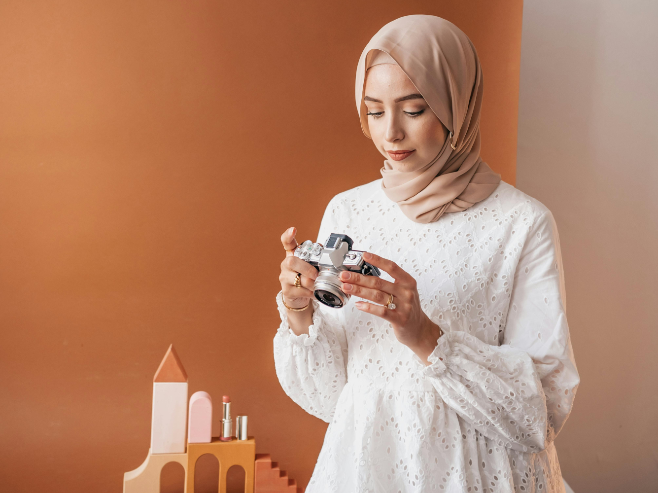 Muslim woman in a hijab photographing a styled setup with a camera, representing creativity, intention, and authentic Islamic content creation.