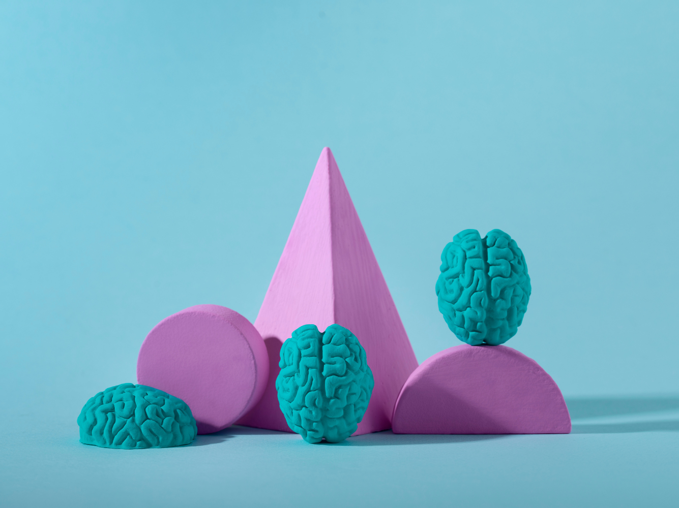 Abstract shapes with small brain models arranged on a blue background, representing brand psychology and the mental processes behind how people perceive and remember brands.